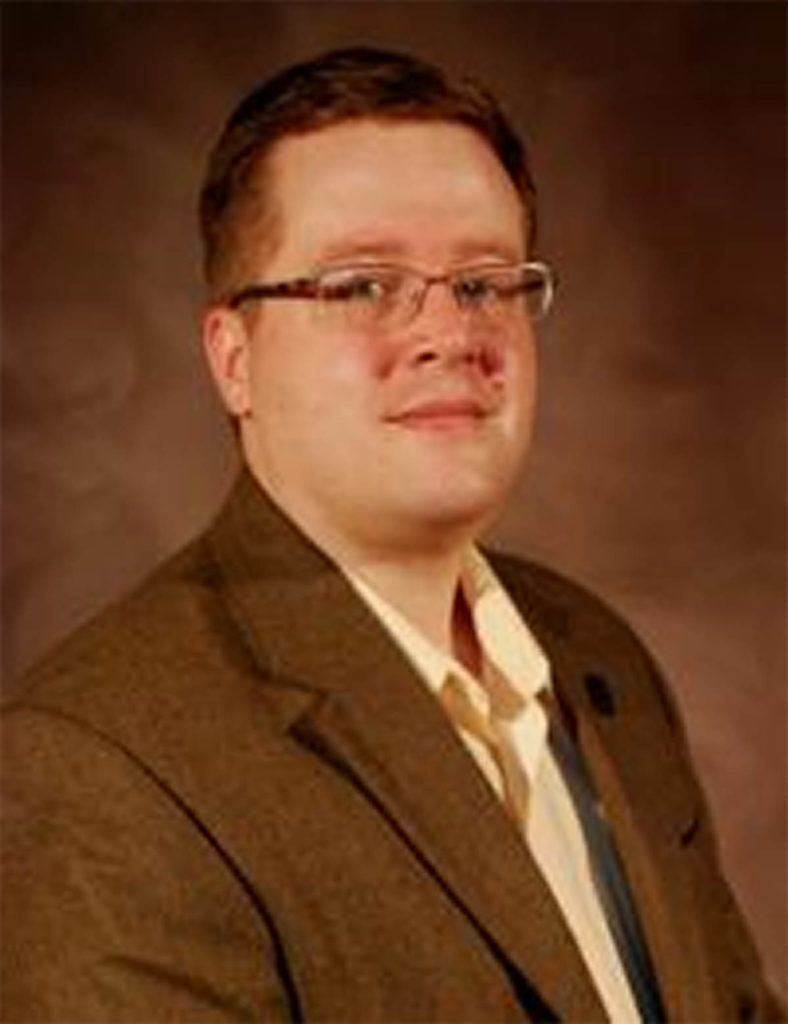 Headshot of Max Grivno, who wears glasses and a brown jacket.
