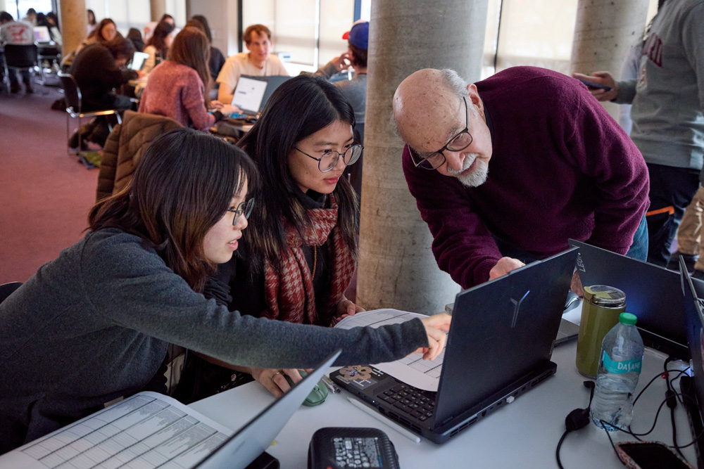 Man and students look at computer screen