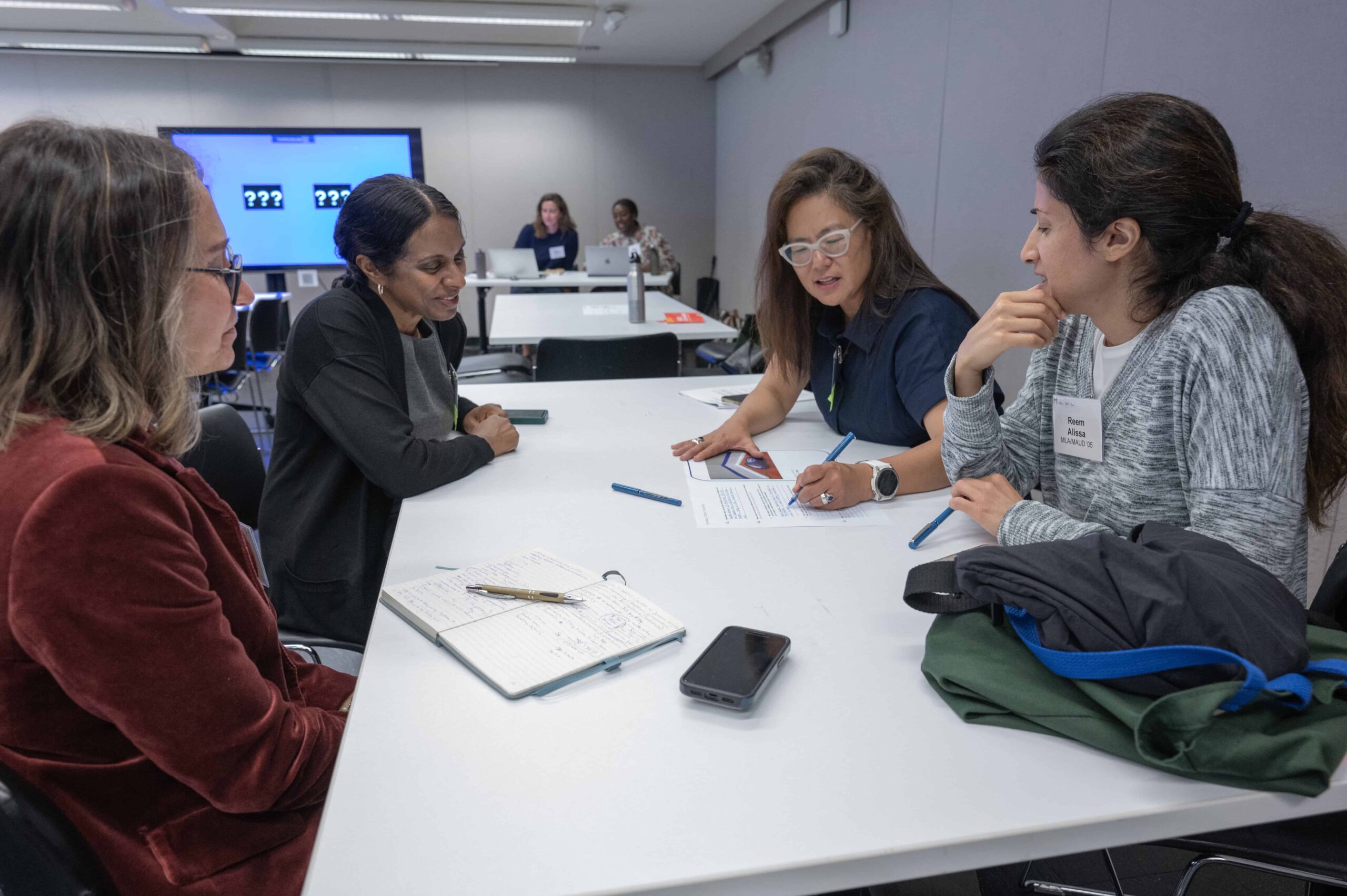 Four alumni gather around a table working on a project