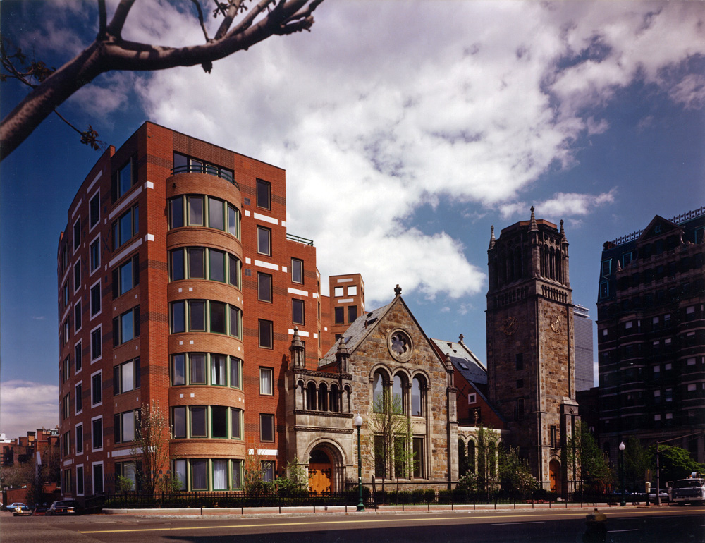 Old stone church with new integrated brick residential tower of seven stories.