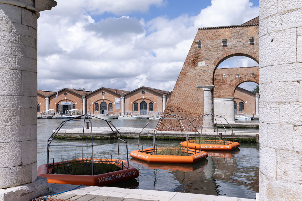 Orange rafts near brick buildings and water.