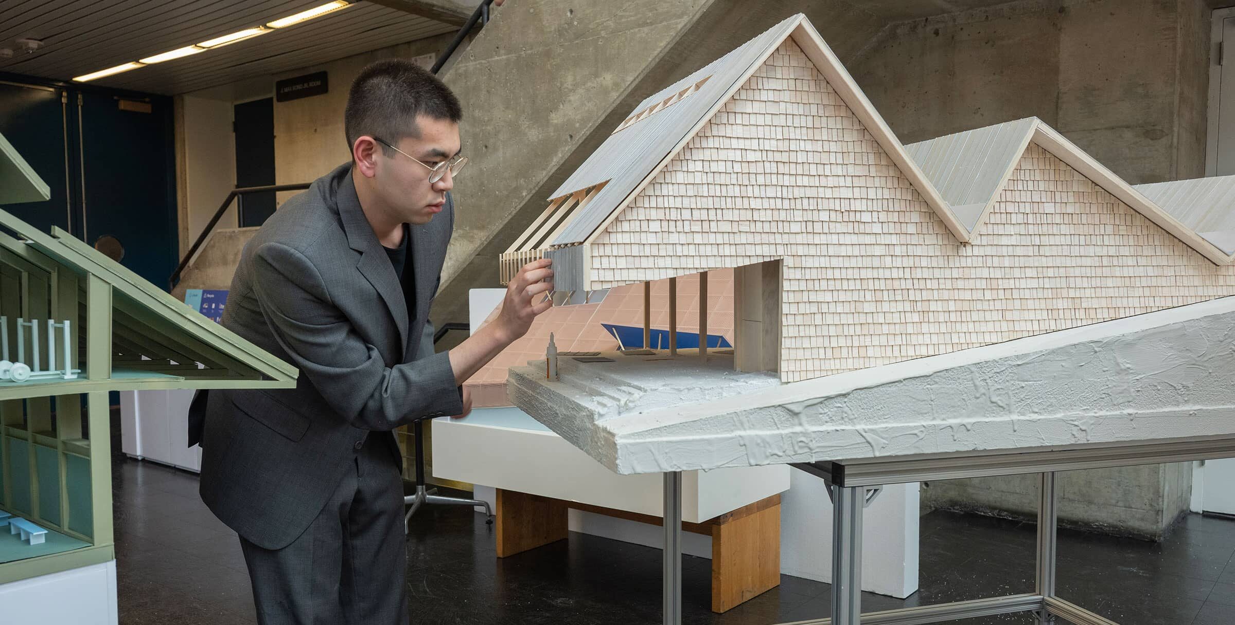 Man working on the fine details of a large scale architectural model.